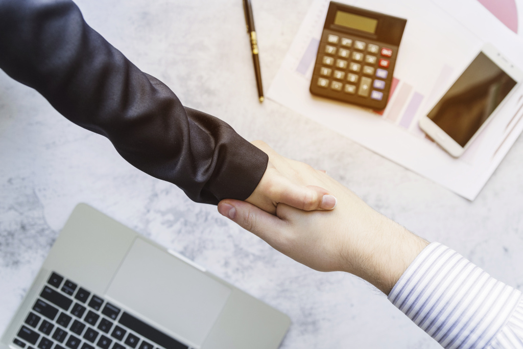 colleagues-shaking-hands-desk.jpg